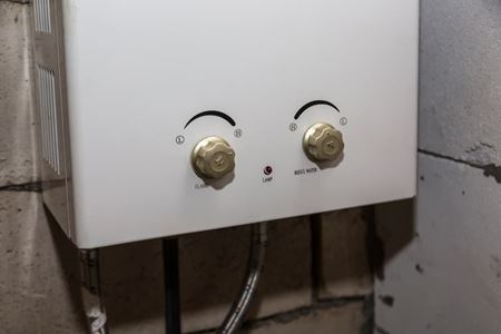 White tankless water heater with controls and pipes, Marietta plumbing service.